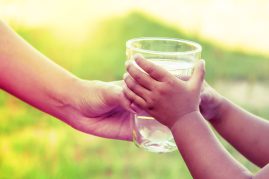 Glass of water being handed from adult to child