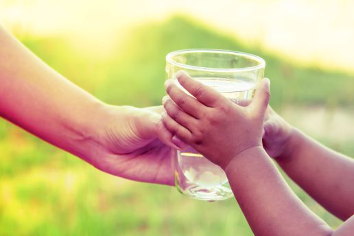 Glass of water being handed from adult to child